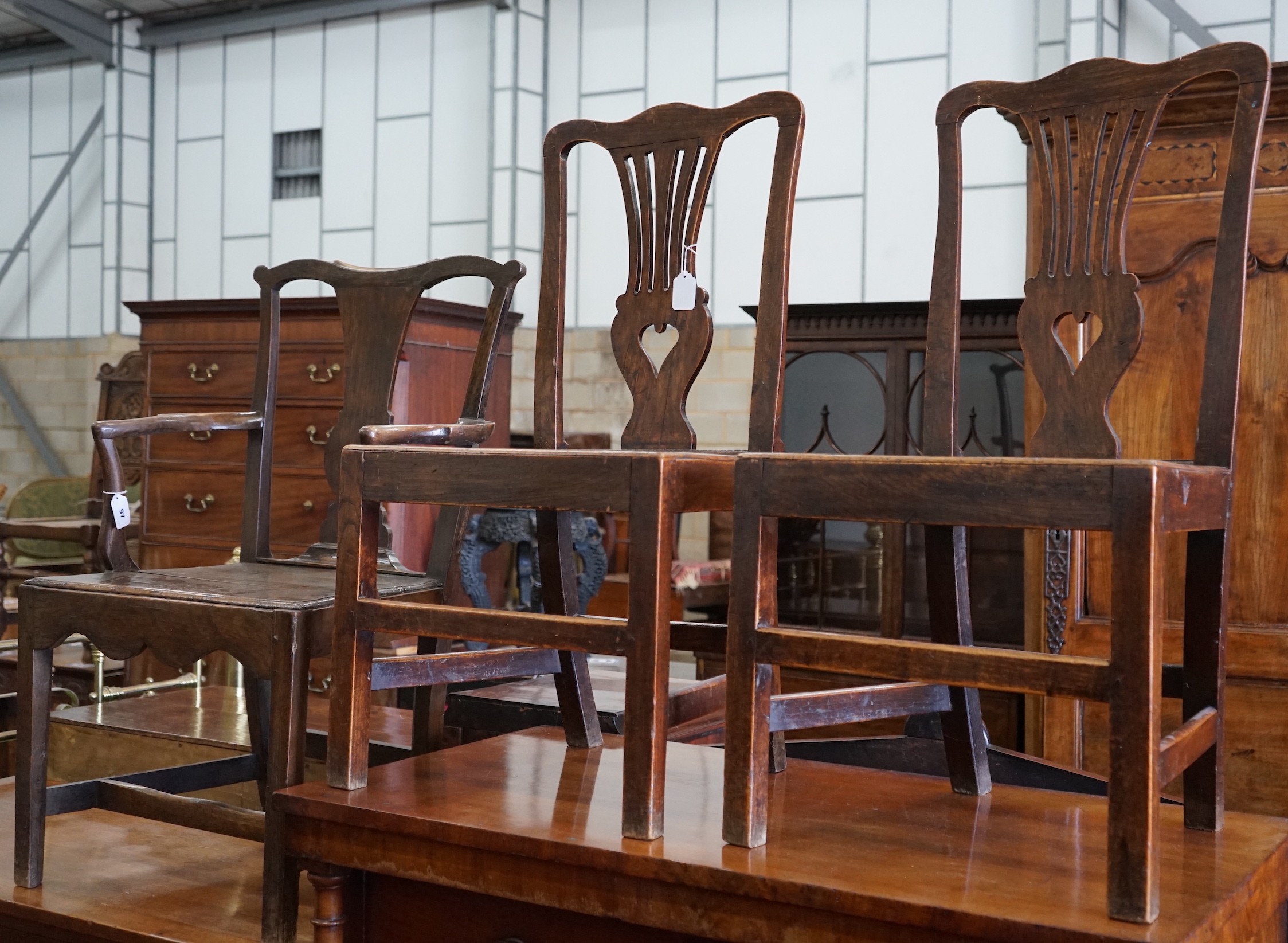 A George III oak open armchair and two similar side chairs